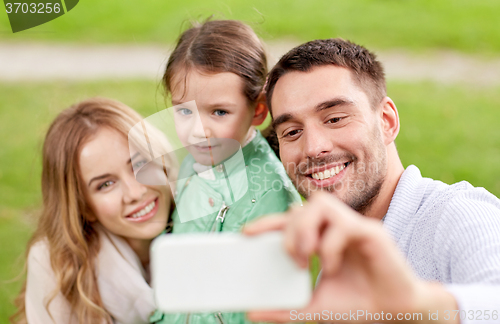 Image of happy family taking selfie by smartphone outdoors