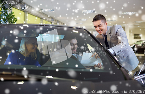 Image of happy couple with car dealer in auto show or salon