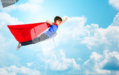 Image of boy in red superhero cape and mask flying over sky