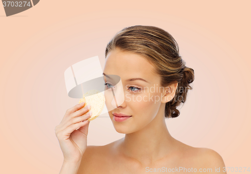 Image of young woman cleaning face with exfoliating sponge