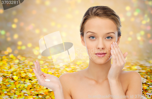 Image of young woman applying cream to her face