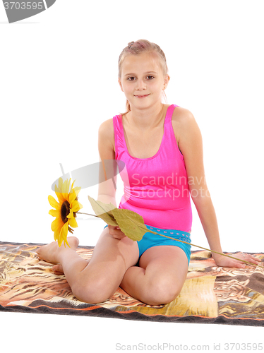 Image of Young girl sitting in bathing suit on a towel.