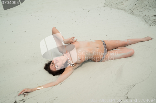 Image of Attractive topless woman relaxes on sand