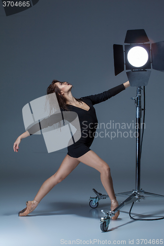 Image of The beautiful ballerina posing on dack blue background  