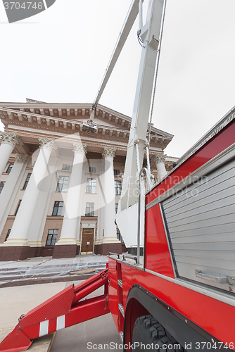 Image of Builders paint building facade by fire truck