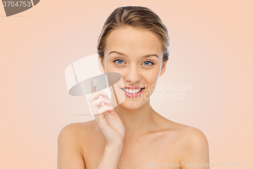 Image of happy young woman applying cream to her face