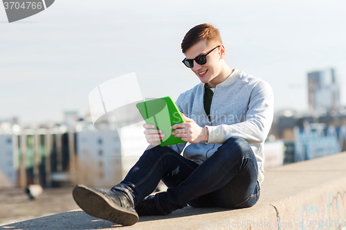 Image of happy young man with tablet pc outdoors