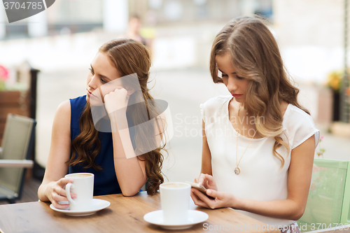 Image of women with smartphones and coffee at outdoor cafe