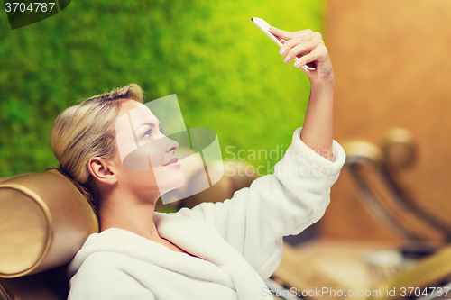 Image of beautiful young woman with smartphone at spa