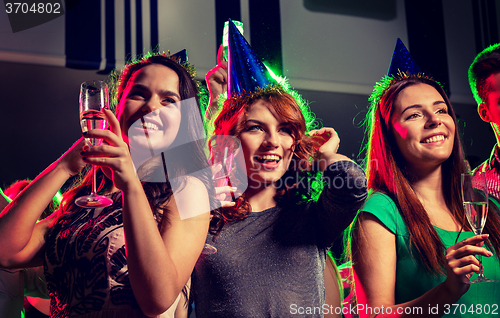 Image of smiling friends with glasses of champagne in club