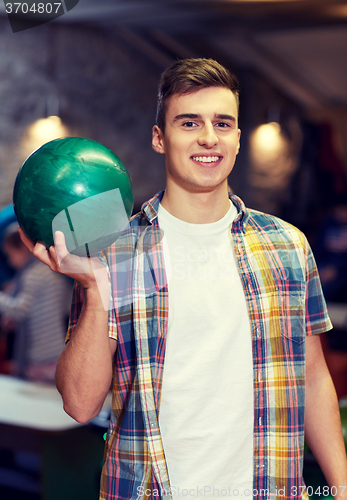 Image of happy young man holding ball in bowling club