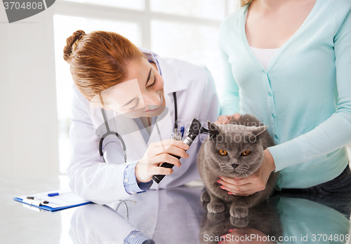 Image of happy woman with cat and doctor at vet clinic