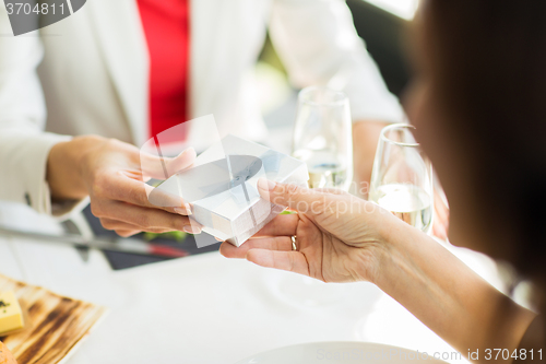 Image of close up of women giving present at restaurant
