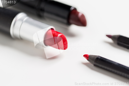 Image of close up of two open lipsticks and lip pencils