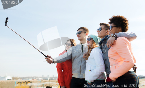 Image of friends taking selfie with smartphone on stick