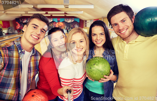 Image of happy friends taking selfie in bowling club