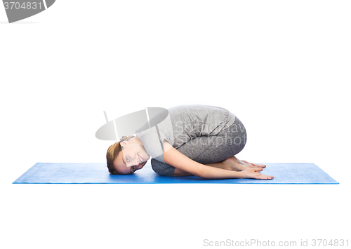 Image of happy woman making yoga in child pose on mat