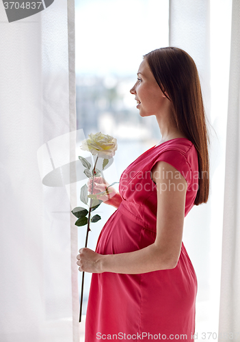 Image of happy pregnant woman with rose flower at home