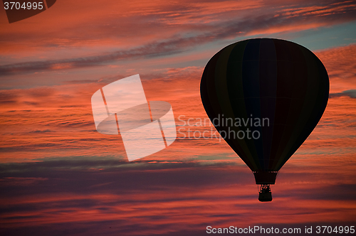 Image of Hot-air ballooning among pink and orange clouds 