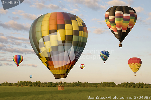 Image of Various hot-air balloons floating over a field