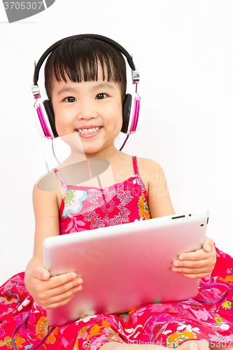 Image of Chinese little girl on headphones holding tablet