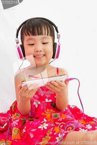 Image of Chinese little girl on headphones holding mobile phone