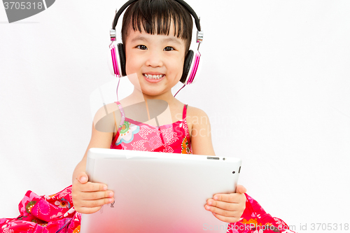 Image of Chinese little girl on headphones holding tablet
