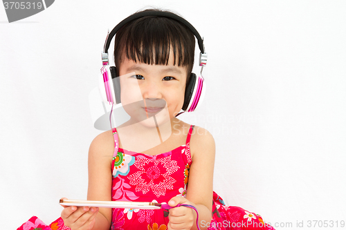 Image of Chinese little girl on headphones holding mobile phone