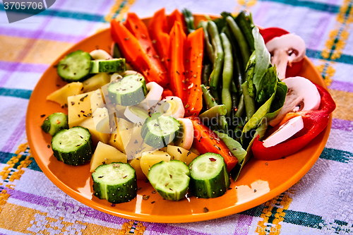 Image of Ladle of steamed freshly harvested young vegetables including crinkle cut sliced carrots, peas and potato batons