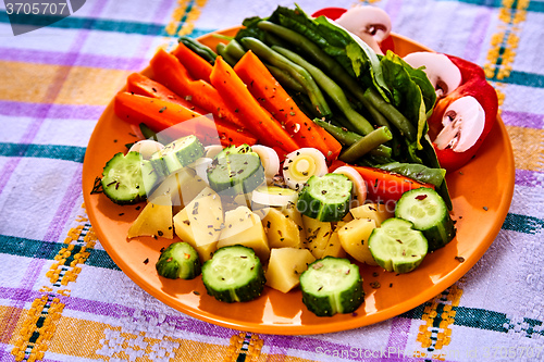 Image of Ladle of steamed freshly harvested young vegetables including crinkle cut sliced carrots, peas and potato batons