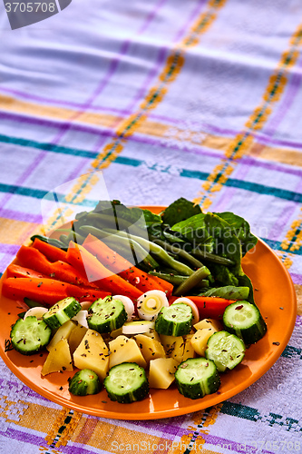 Image of Ladle of steamed freshly harvested young vegetables including crinkle cut sliced carrots, peas and potato batons