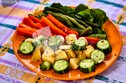 Image of Ladle of steamed freshly harvested young vegetables including crinkle cut sliced carrots, peas and potato batons