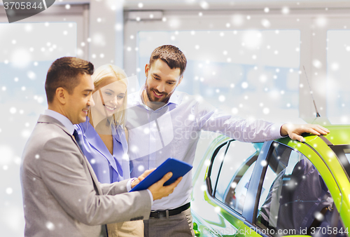 Image of happy couple with car dealer in auto show or salon