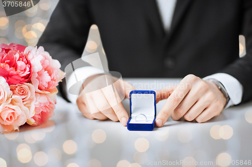 Image of close up of man with gift box and engagement ring