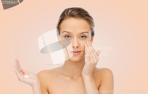 Image of young woman applying cream to her face