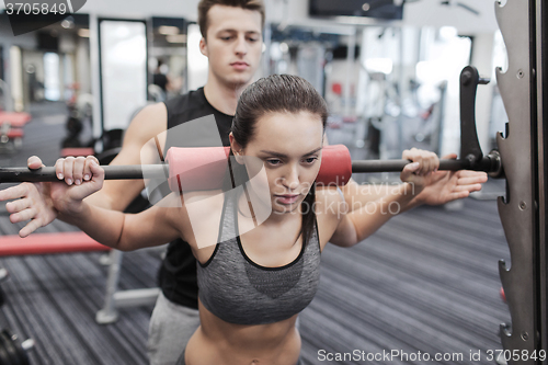 Image of man and woman with barbell flexing muscles in gym