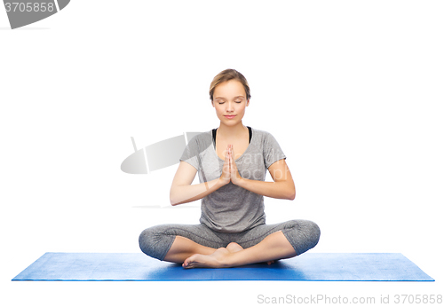 Image of woman making yoga meditation in lotus pose on mat