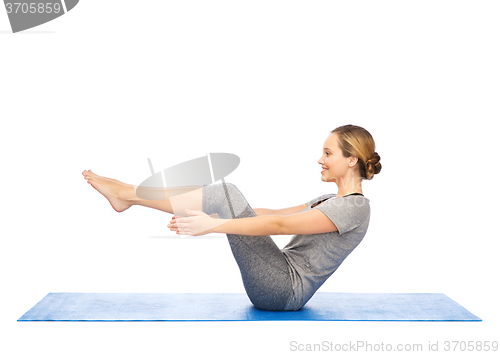 Image of woman making yoga in half-boat pose on mat