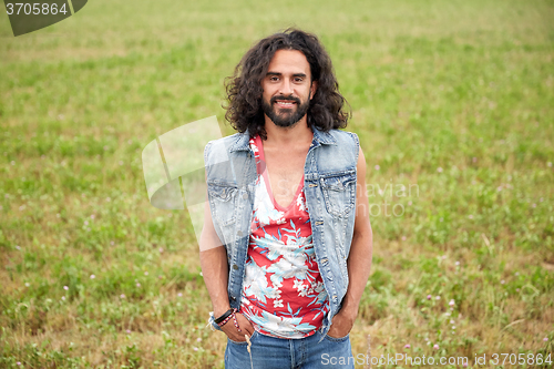 Image of smiling young hippie man on green field