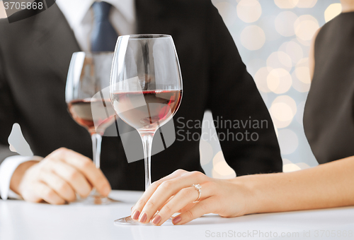 Image of hands of couple with diamond ring and wine glasses