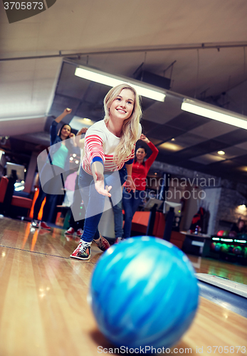 Image of happy young woman throwing ball in bowling club