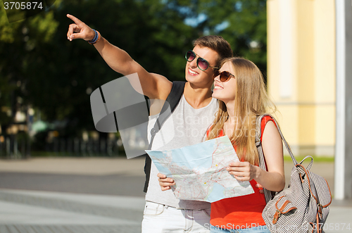 Image of smiling couple with map and backpack in city