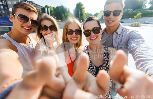 Image of happy friends taking selfie and showing thumbs up