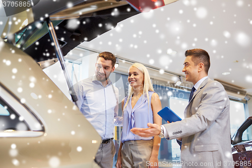 Image of happy couple with car dealer in auto show or salon