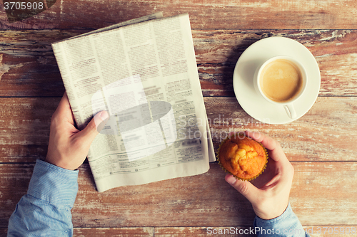 Image of close up of male hands with newspaper and coffee