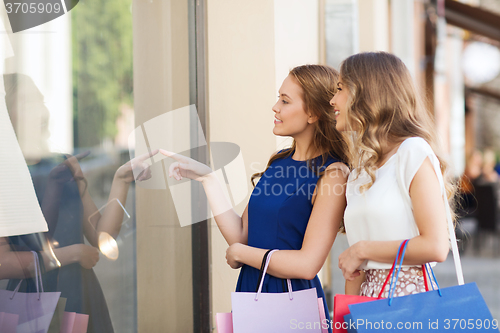 Image of happy women with shopping bags at shop window