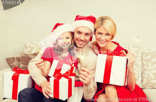 Image of smiling family holding gift boxes and sparkles