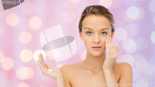 Image of young woman applying cream to her face