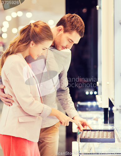 Image of happy couple choosing engagement ring in mall