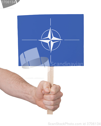 Image of Hand holding small card - Flag of NATO